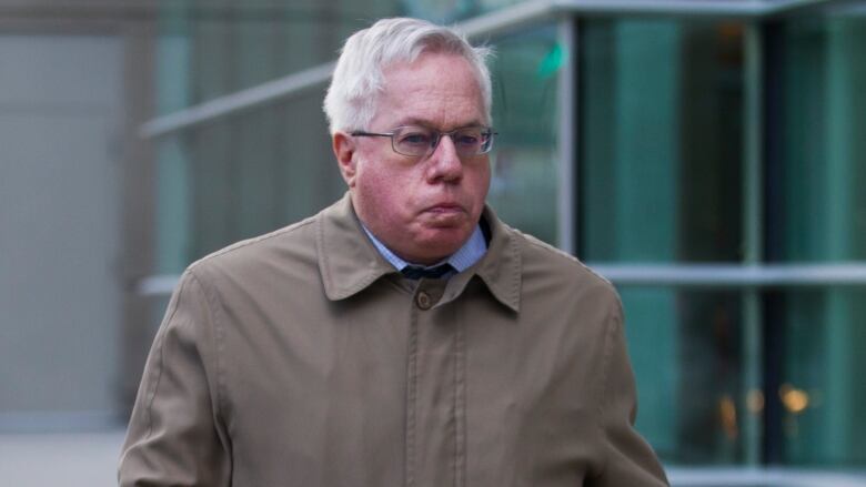 A man in a trench coat walks by the Calgary courthouse.