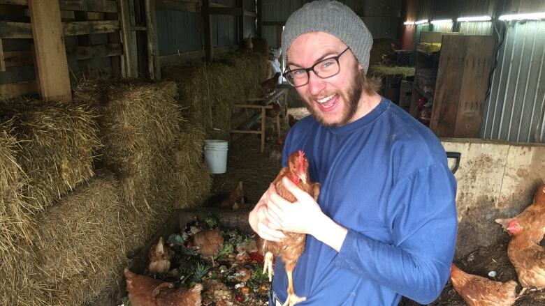 Dane Fader holds up one of his beloved chickens at the GreenerBins Farm.