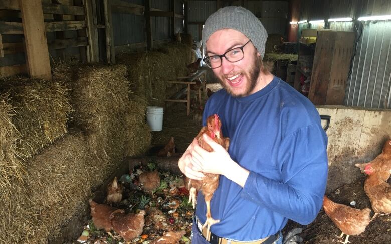 Dane Fader holds up one of his beloved chickens at the GreenerBins Farm.