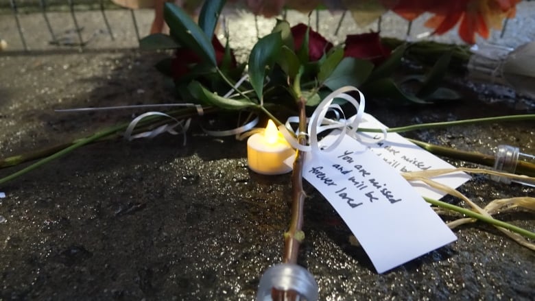 A note attached to a red rose says 'you will be missed and forever loved'