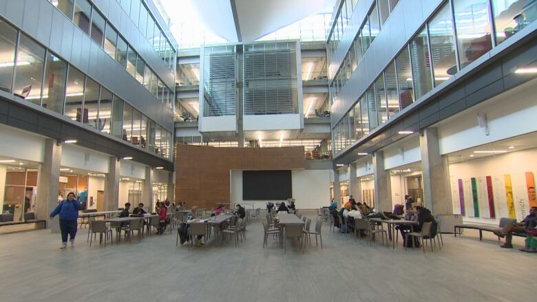 A large hall filled with tables and people seated in chairs at NorQuest College.