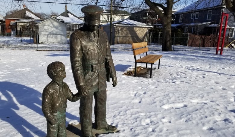 A bronze statue of a man in a police uniform holding a child's hand.