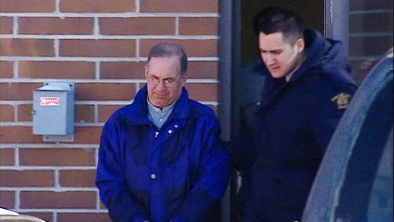 In this archival image from 2001, Kenneth Mackinnon Mealey walks out of the Selkirk, Man. courthouse in handcuffs after being sentenced to 2 1/2 years in prison for sexually assaulting five boys in Manitoba and one in Ontario.