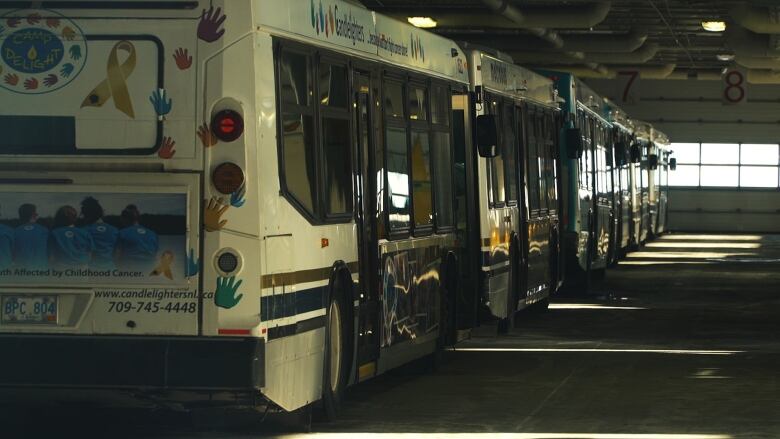 A line of city buses inside a garage. 