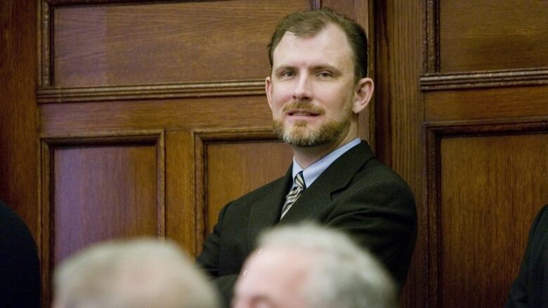 Prime Minister Stephen Harper's Chief of Staff, Ian Brodie watches from the back of the room, a photo-op before the government caucus meeting on Parliament Hill in Ottawa Wednesday March 5, 2008.