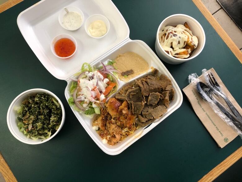 Styrofoam containers of salad, potatoes drizzled in a creamy sauce, and a mix of chopped up meat, rice, hummus and salad.