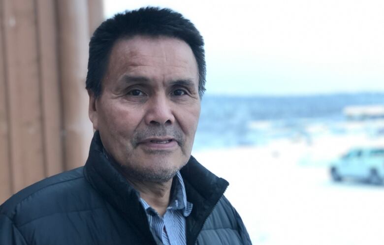 Man standing near a structure with snow in the background.