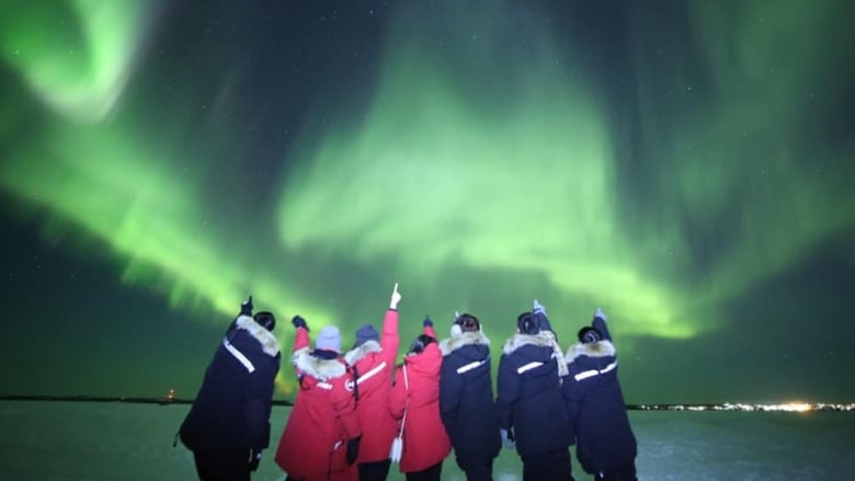 Tourists take a picture in under the northern lights in the winter