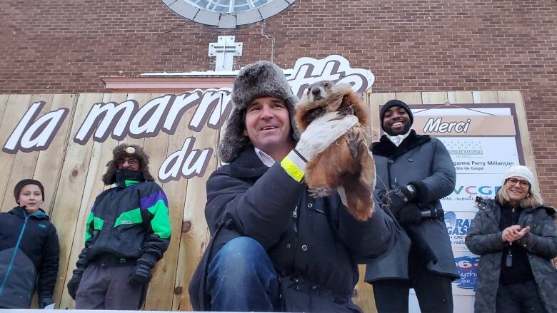 Man holds up brown groundhog at festival