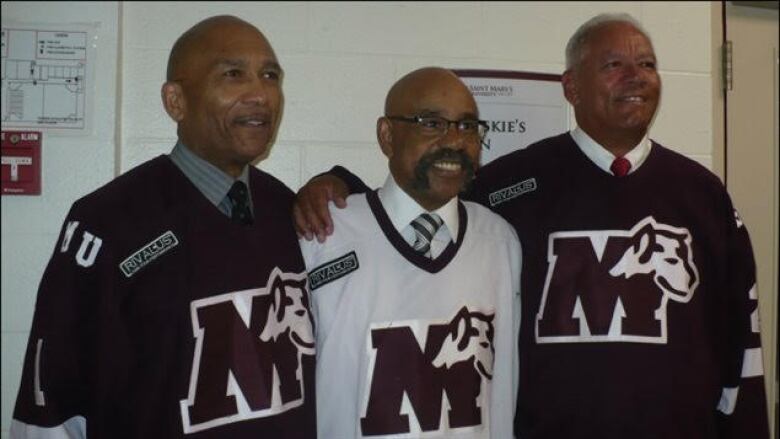 Three Black men wearing hockey jerseys