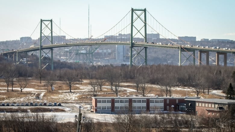 A steel truss bridge, with a low-rise building in the foreground.