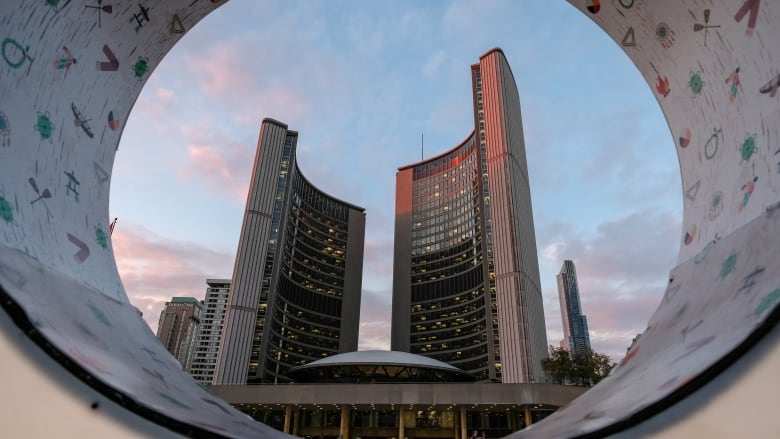 Toronto city hall building, as seen through letters of the TORONTO sign in Nathan Phillips Square.