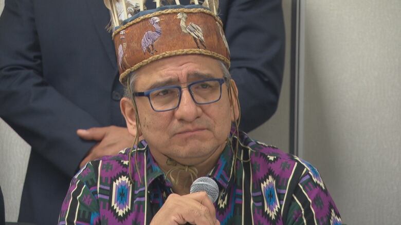 Man wearing a headress grips a microphone.