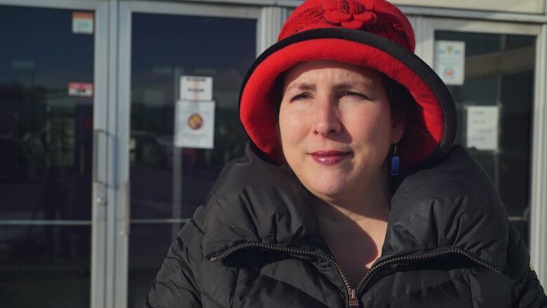 A woman with a red hat poses for an outside photo.