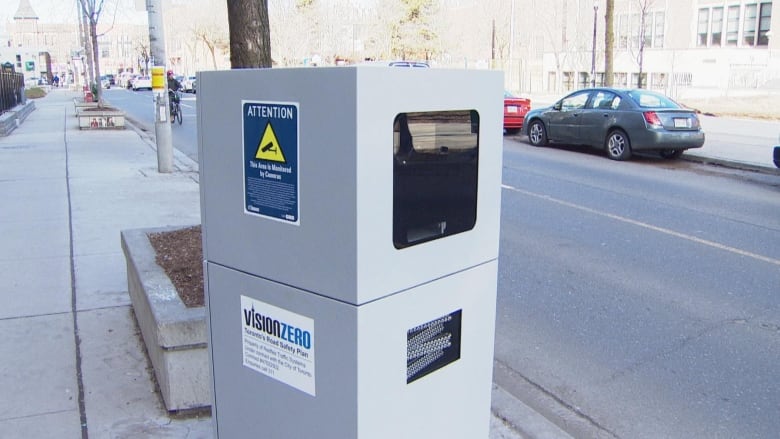 A silver automated speed camera sits on a Toronto street.