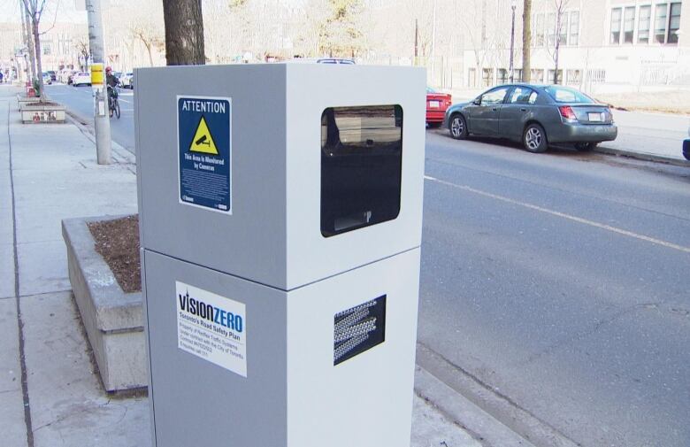 A silver automated speed camera sits on a Toronto street.