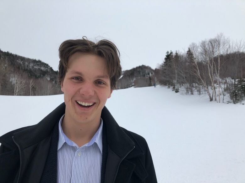 A smiling man is shown outside at a ski hill.