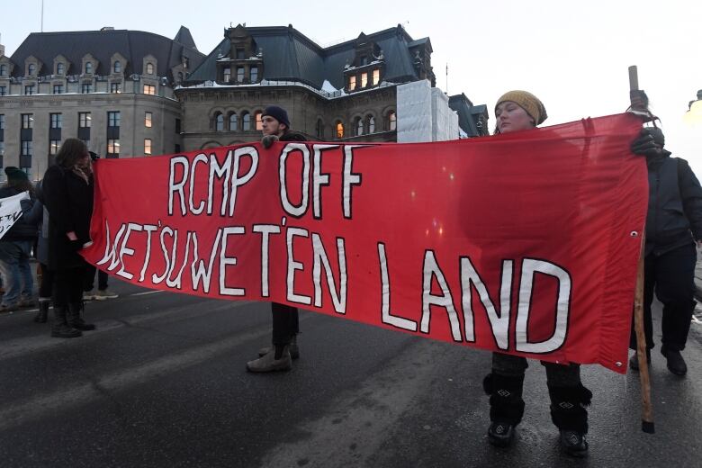 Protesters hold a big red banner reading, 