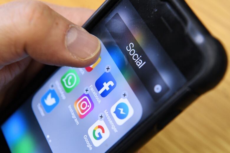 A close-up of a smartphone, showing some social media apps like Facebook, Instagram and WhatsApp.