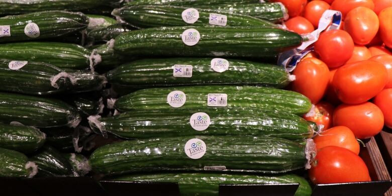 Cucumbers and tomatoes on grocery store shelves.