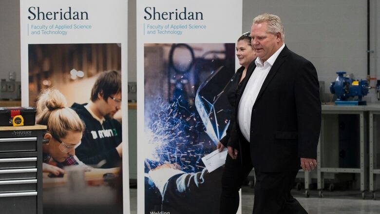 Doug Ford walks past two signs that say 'Sheridan'