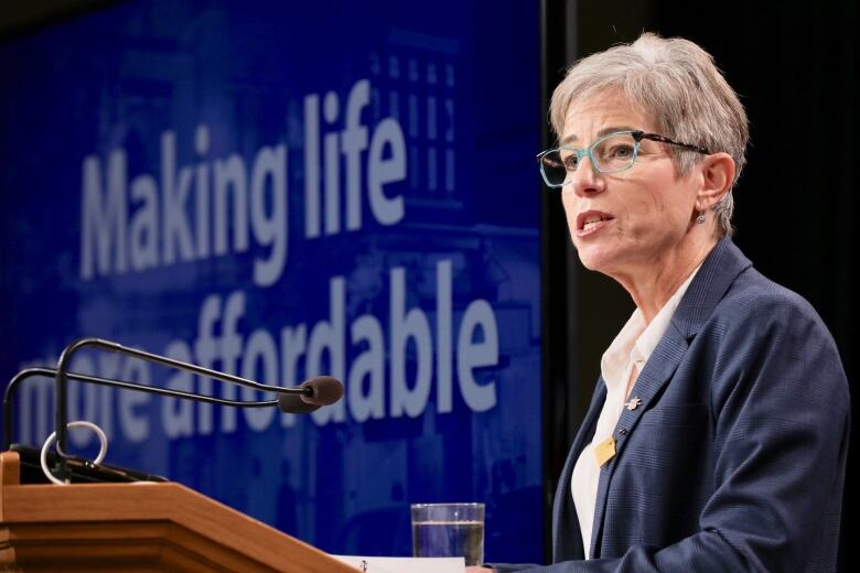 Selina Robinson stands at a podium, with a slide behind her that reads 'Making life more affordable'. She is a white woman with short hair, wearing a navy blue jacket.