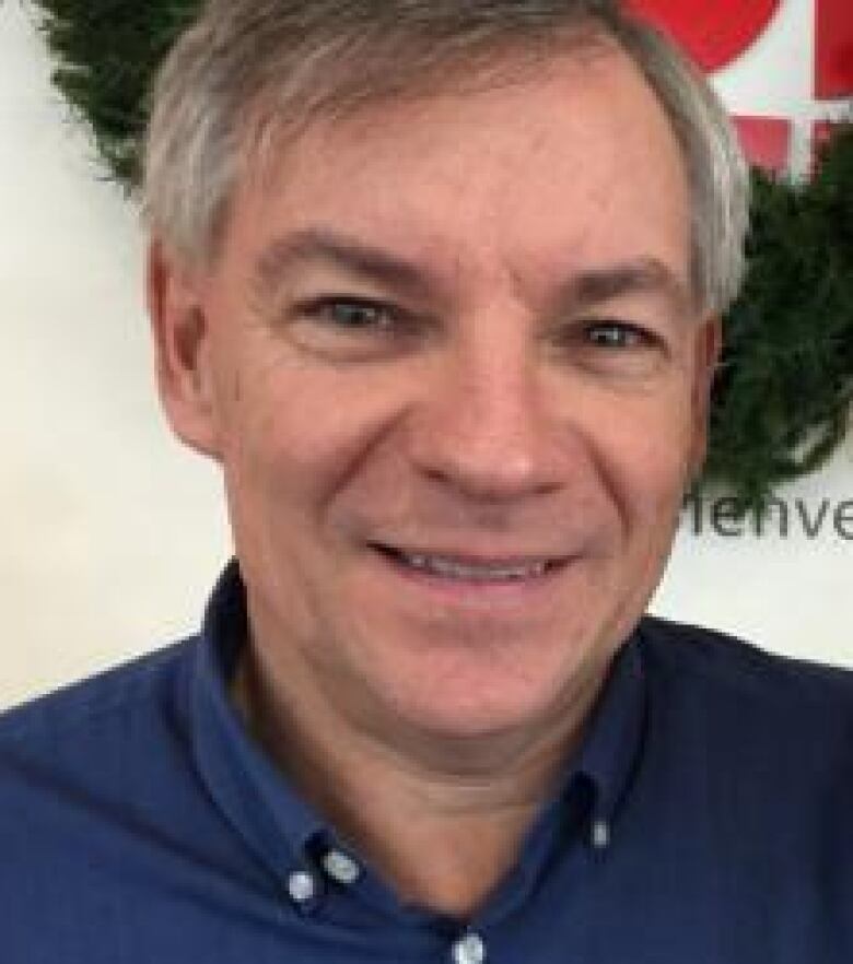 A picture of Robert Doyle, a pharmacist in St. John's with the Neighbourhood Pharmacy. He has salt and pepper hair and is smiling, wearing a blue shirt.