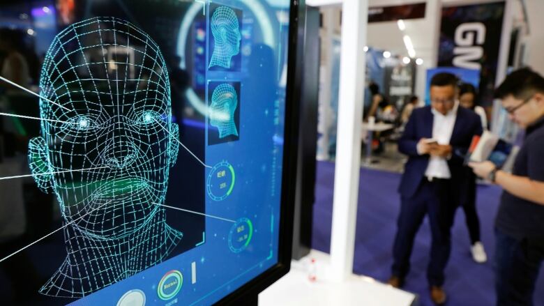 Visitors check their phones behind the screen advertising facial recognition software during Global Mobile Internet Conference (GMIC) at the National Convention in Beijing, China April 27, 2018.