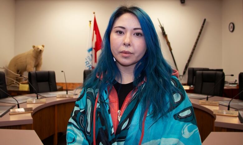 Woman with blue hair stands in council chambers