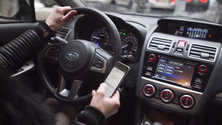 A driver texts while at the wheel in this photo illustration in Montreal on January 25, 2017. Manitoba drivers who use a hand-held cell phone behind the wheel will face stiffer penalties as of Nov. 1.The fines will jump to $672 from $203, and the number of demerit points will increase to five points from two. THE CANADIAN PRESS/Paul Chiasson