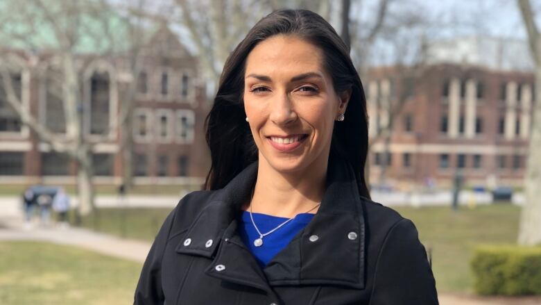 Woman stands on campus of University of Windsor and smiles. 