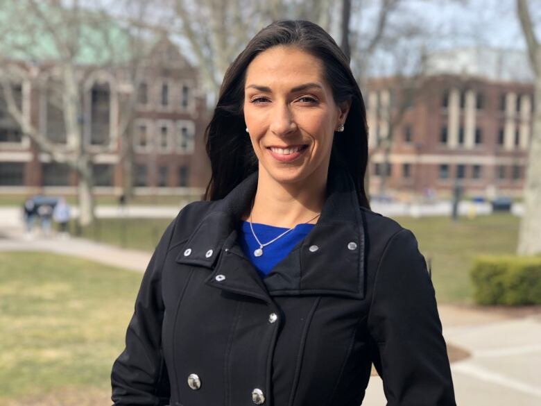 Woman stands on campus of University of Windsor and smiles. 