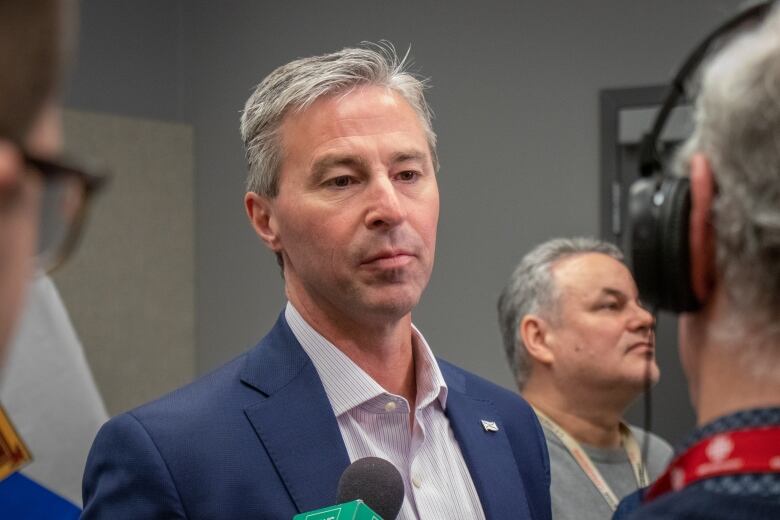 A white man with grey hair wearing a navy suit