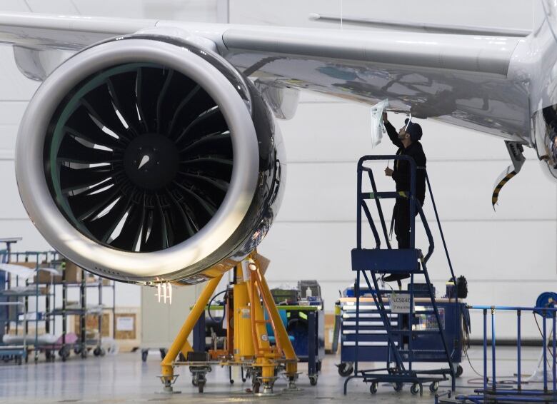 An Airbus employee works under the wing of an Airbus A220 at the assembly plant in Mirabel, Que., Feb. 20, 2020. 