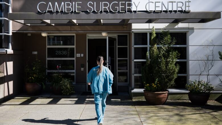 A woman walks into a building called the Cambie Surgery Centre