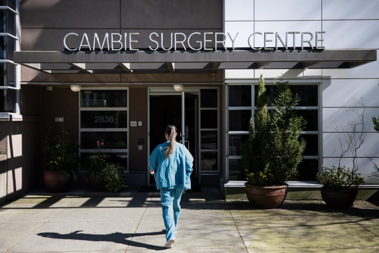 A woman walks into a building called the Cambie Surgery Centre