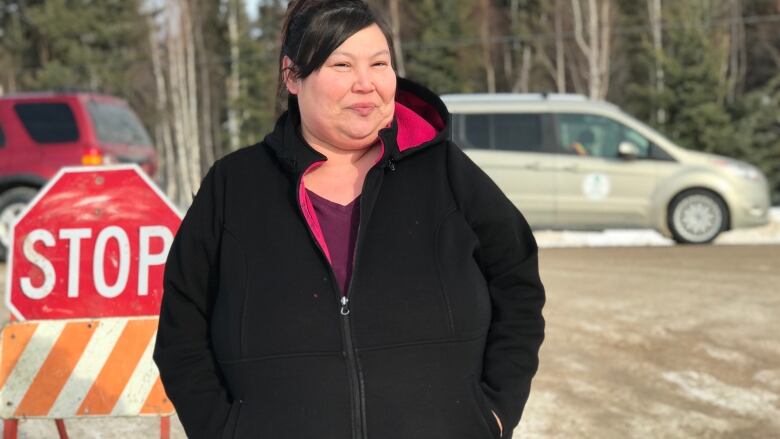 April Martel, chief of Kt'odeeche First Nation, stands in front a barricade and stop sign.