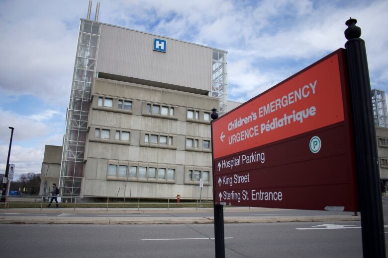 A hospital seen from across a road, with a sign reading 