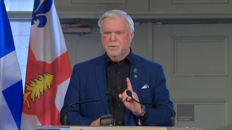 older white man with white hair and beard speaks at a press conference