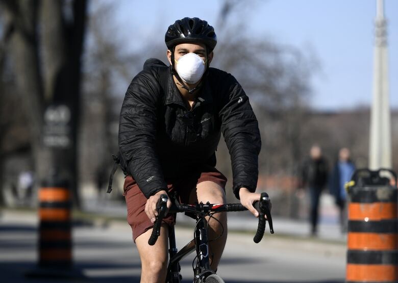 A masked cyclist rides toward the camera.