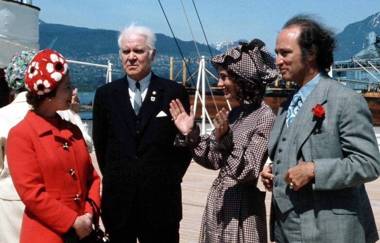 Four well-dressed people on deck of boat