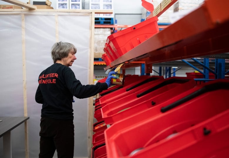 A woman holds a can in a storehouse.