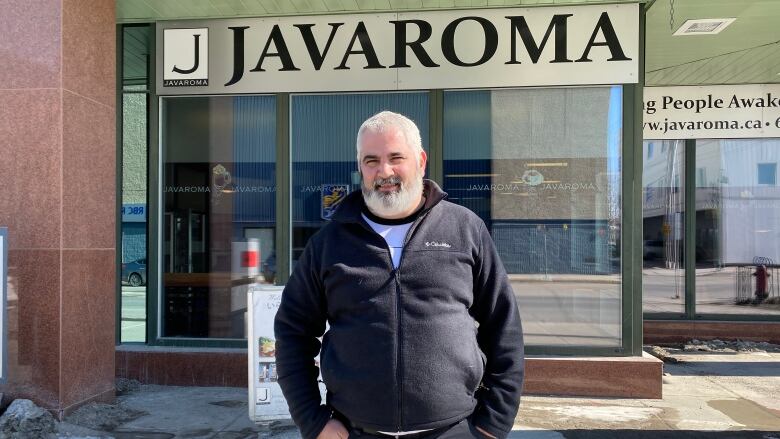 older man stands in front of his coffee shop Javaroma. 