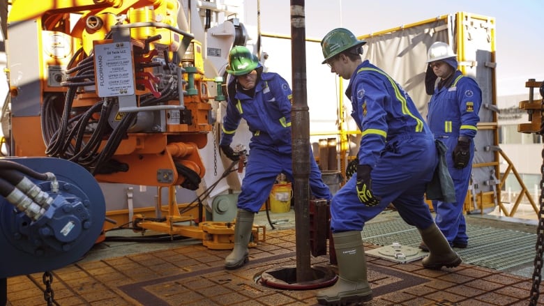 People in safety gear work outdoors.