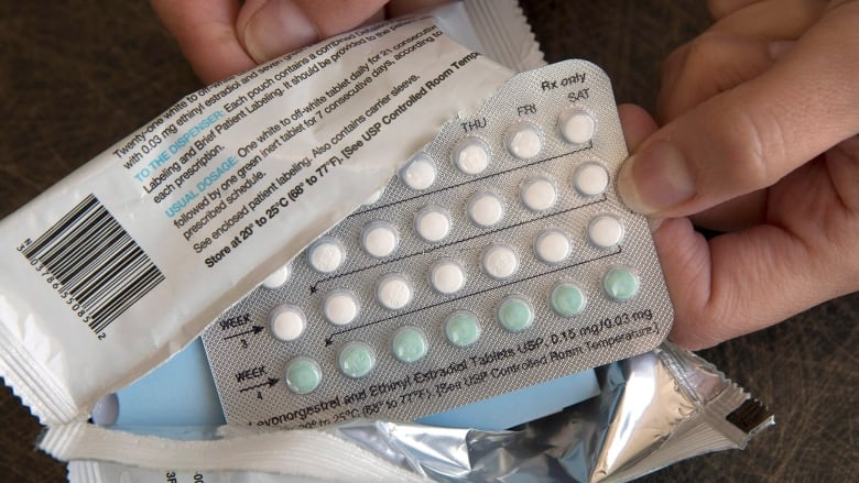 a person holds packets of white and blue pills