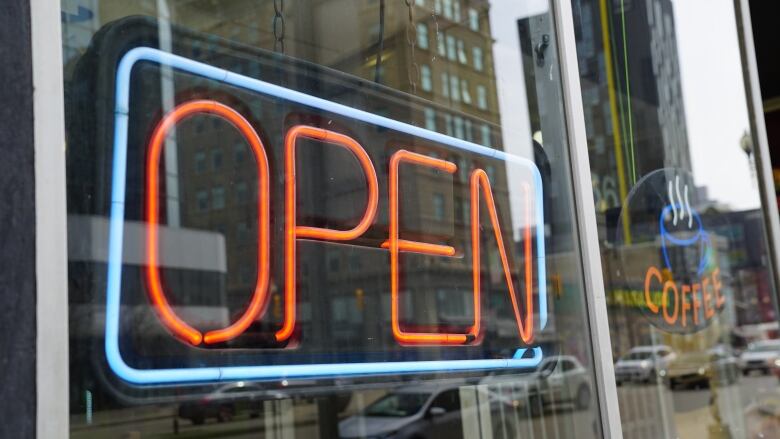 Neon open sign lit-up in a coffee shop window.