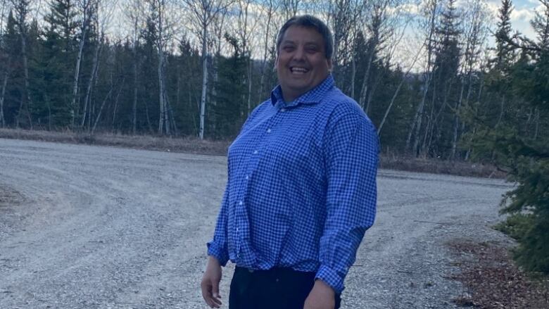 A man stands on a gravel road.