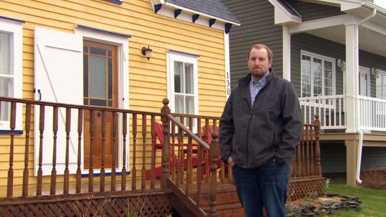 Man standing with his hands in his pockets outside a house.