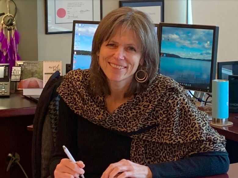 A woman holding a pen while sitting at a desk.