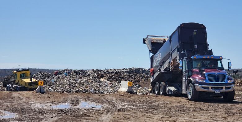 A garbage truck drops off more waste at a landfill.